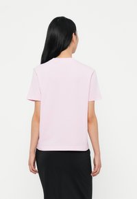 Ανοιχτό ροζ βαμβακερό t-shirt με χαλαρή εφαρμογή, κοντά μανίκια και ευθεία ραφή. Μινιμαλιστικός σχεδιασμός, ομαλή υφή και χωρίς ορατά γραφικά.