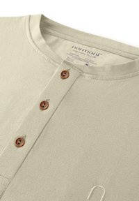 Hellgrünes Langarmshirt mit gerippter Textur, runden Ausschnitt, vier braunen Knöpfen und dezentem Stickdetail.
