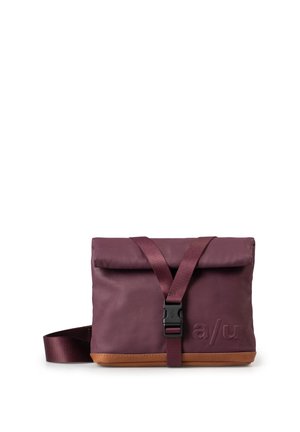 Borsa a tracolla viola scuro realizzata in tessuto resistente, dotata di un coperchio, di una tracolla regolabile e di una base in pelle marrone con dettagli del logo in rilievo.