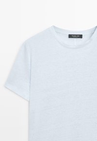 T-shirt bleu clair à manches courtes et col rond, avec une étiquette noire Massimo Dutti cousue à l'intérieur du col au dos.