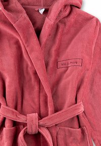 Koraalkleurige badjas van badstof met een capuchon, voorzien van een bijpassende riem, zijzakken en een patch met de tekst "minder is meer." Gelaagd textiel.