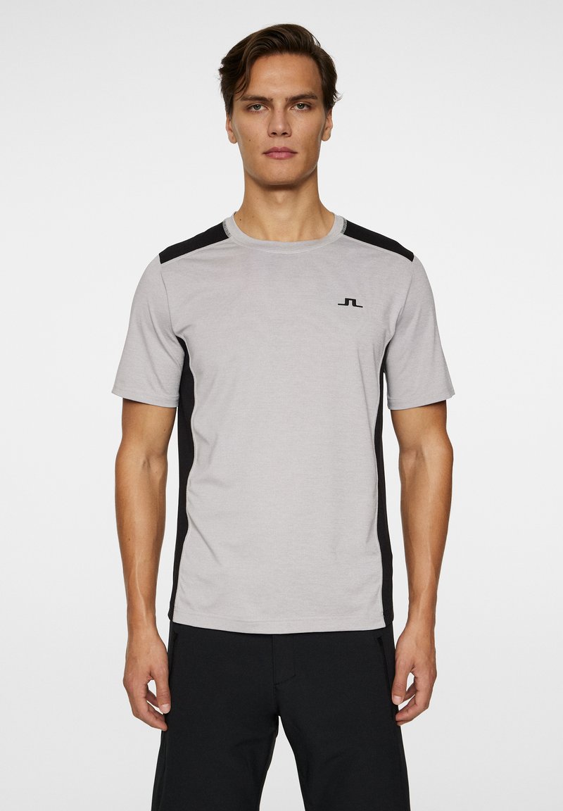 Grå sportströja med svarta sidopaneler och korta ärmar. Har en rund halsringning och en liten logotyp på bröstet.