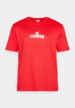 Rde majica iz bombaža s kratkimi rokavi, ki ima na sredini prsnega dela bel logo "CHAMPION", ter okroglo ovratnico.