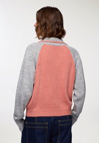 Cardigan lavorato a maglia con parte anteriore e maniche grigio chiaro, caratterizzato da un retro corallo, orlo a costine e texture a contrasto sulle spalle.