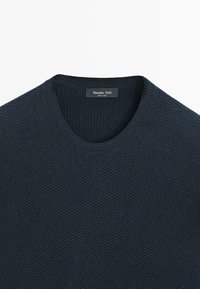 Maglione blu navy a maglia con scollo rotondo a costine, motivo testurizzato e una discreta etichetta con il marchio sul colletto.