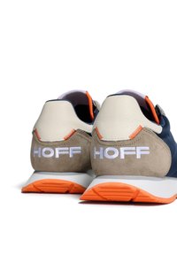 Sneakers in navy and beige suede with leather accents; features a white logo and orange detailing on the sole and stitching.