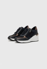 Baskets compensées en bleu foncé avec des accents métalliques. Elles présentent un motif texturé, un devant à lacets et une fermeture éclair sur le côté pour un accès facile.