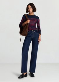 Striped sweater in navy and red, high-waisted dark denim jeans, and black loafers. Brown suede bag. Straight-leg fit and smooth texture.