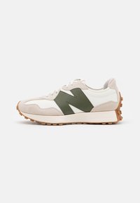 Béžovo-bílá teniska se zeleným logem, béžovou gumovou podrážkou, semišovými detaily a bílými tkaničkami, zobrazená z boku na bílém pozadí.