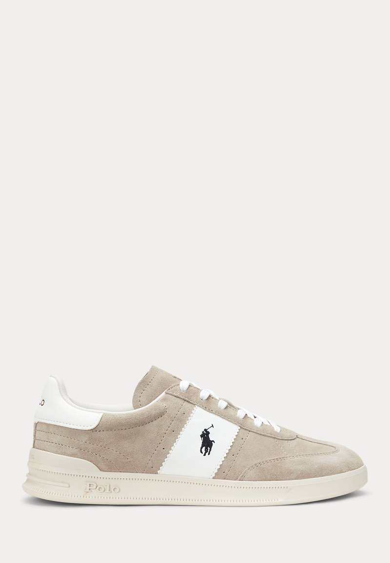 Beżowy zamszowy sneaker z białym skórzanym obcasem i bocznym paskiem, białymi sznurowadłami oraz czarnym logo Polo z boku.