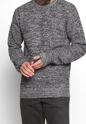 Grijs-zwart gebreide trui met lange mouwen, geribbelde boorden en een ronde halslijn, met een gestructureerd, gemêleerd patroon.