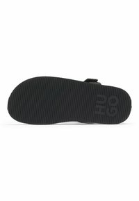 Svart gummisula för sneakers med horisontella ränder; har präglad "Hugo"-logotyp. Slät yta med rundad form och robust konstruktion.
