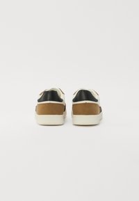 Baskets avec une tige en cuir noir, des accents en suède marron et une semelle en caoutchouc crème ; design minimaliste avec un bout arrondi et un talon rembourré.