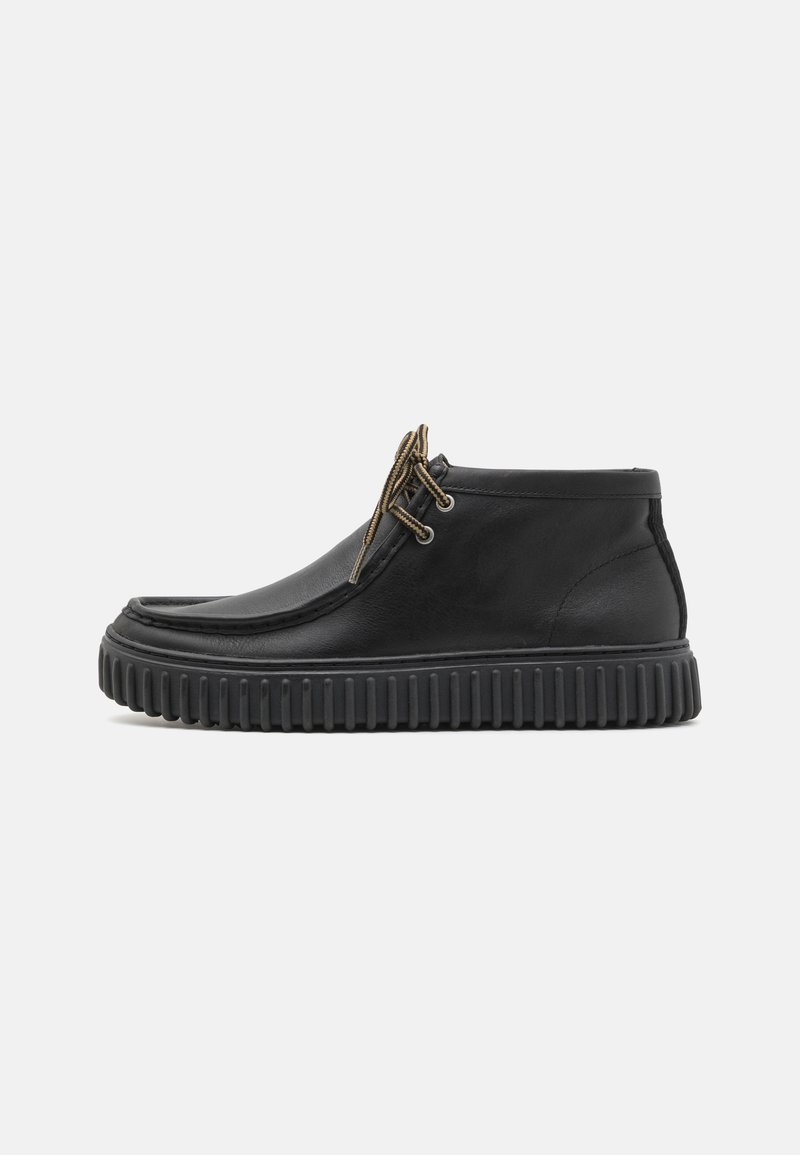 Bottines en cuir noir à bout rond, avec des lacets exposés, une semelle texturée et une tige lisse avec des détails subtils.