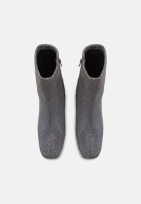 Paire de bottines en tissu gris avec fermetures éclair latérales, vues de dessus sur un fond blanc.