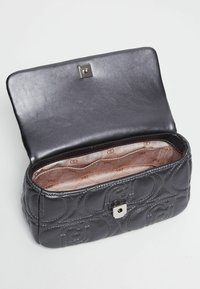 Borsa nera in pelle trapuntata con chiusura a scatto in argento, caratterizzata da una fodera interna a motivo. Il design aperto rivela ampio spazio di archiviazione.