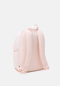 Růžový látkový batoh s polstrovanými popruhy, zakulaceným tvarem, bočními kapsami a horním úchytem pro snadné nošení. Měkká textura.