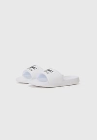 Sandales blanches à glissière en matériau synthétique, avec une large sangle arborant un logo de crocodile noir et une semelle texturée pour une meilleure adhérence.