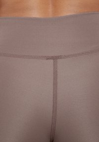 Leggings a vita media in un colore mauve tenue, realizzati in un tessuto morbido ed elastico. Presentano cuciture piatte e una cintura ampia per il comfort.