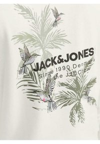 Camiseta de algodón blanca con un diseño tropical que presenta hojas de palmera verdes y colibríes con acentos rosas. Texto: "JACK & JONES Desde 1990".