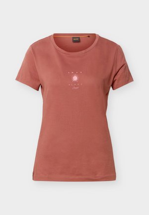 Camiseta de manga corta color óxido con cuello redondo y un pequeño gráfico de sol rosa con el texto "AMAR EL SOL" en el pecho.