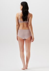 BH och matchande boyshorts i mjukt, lätt mauve-tyg. Sömlös design med justerbara band och en bred midjeband, med subtila sömnadsdetaljer.