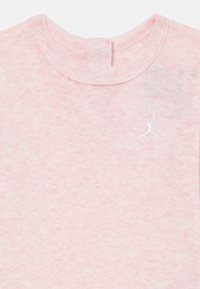 Rosa bomullströja med en subtil melerat textur, som har en vit broderad Jumpman-logotyp på bröstet och en ribbad rundhals.