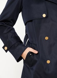 Navy waterproof trench coat with gold-tone buttons, wide collar, and multi-pocket design. Smooth texture and tailored fit.