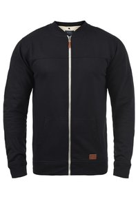 Laivastonsininen vetoketjullinen collegepaita puuvillasekoitetta, jossa pyöreä pääntie, kaksi etutaskua, kontrastivärinen vetoketju ja pieni nahkainen brändilogo.