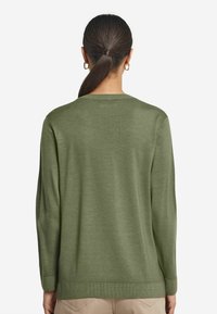 Zielony sweter z dzianiny o luźnym kroju, z długimi rękawami i okrągłym dekoltem. Gładka tekstura i subtelne prążkowane detale przy mankietach i dolnym wykończeniu.