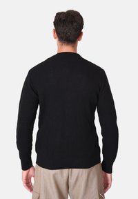 Maglione nero a coste con maniche lunghe, scollo tondo e orlo dritto. La texture appare spessa e strutturata, mostrando un design casual.