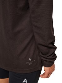 Close-up of a person wearing a long-sleeve textured dark brown top with "Sorona Agile" logo near the hem and black athletic shorts.