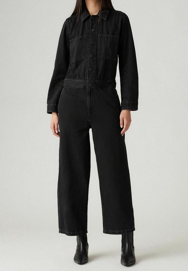 Schwarzer Jeans-Overall mit langen Ärmeln, Knopfleiste, zwei Brusttaschen, losem weit geschnittenem Bein und robusten Nähdetails.