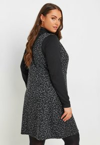 Musta mekko harmaalla kukkakuviolla, olkaimeton malli ja kapea istuvuus. Mallilla on pitkähihaisen paidan alla.