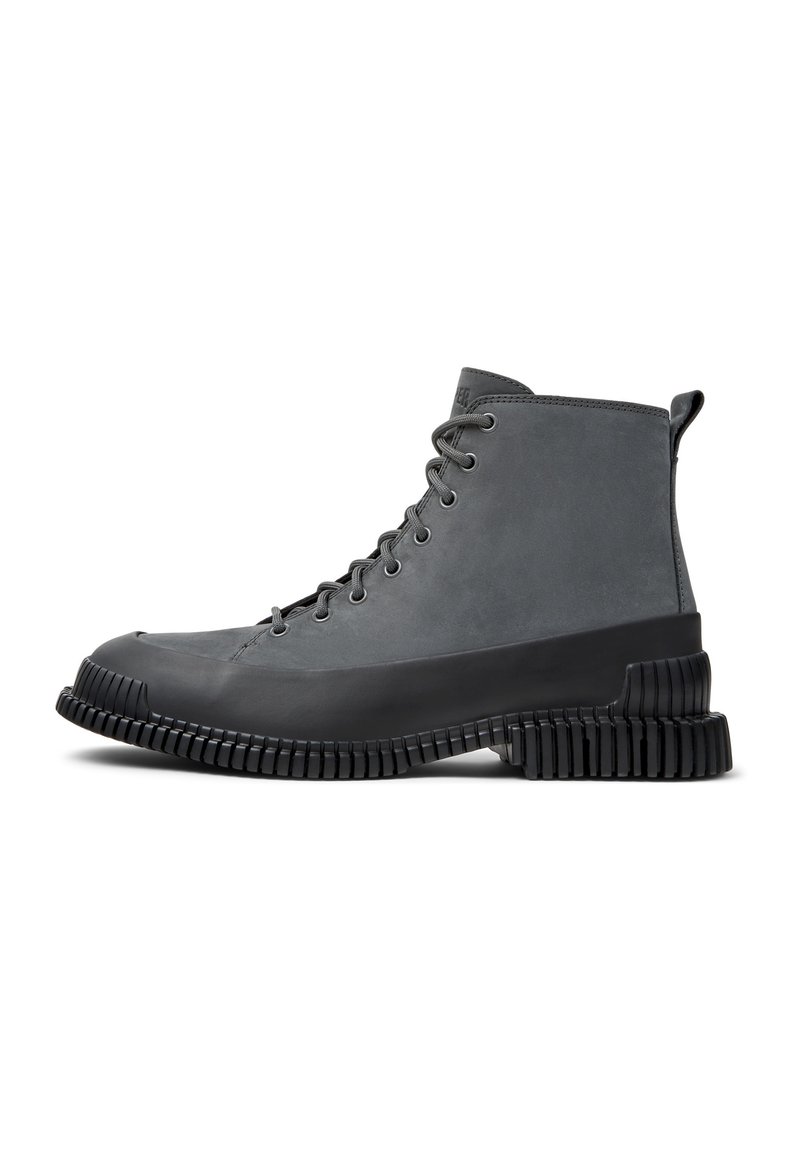 Botas de tobillo grises con parte superior de cuero suave, puntera redonda, suela de goma gruesa y un diseño acanalado texturizado para mejorar la tracción.
