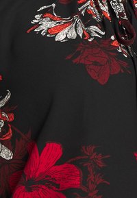 Tela negra con un patrón floral en rojo y blanco, con contornos y texturas detalladas de flores. El diseño incluye un escote fruncido.