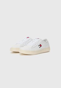 Vita sneaker i slät läder med låg profil och rund tå. Har tonade snören och en logotypapplikation i röd, vit och blå färg.