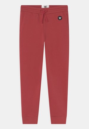 Rote, konisch zulaufende Jogginghosen mit Kordelzugbund, Seitentaschen, elastischen Bündchen und einem kleinen runden Logo-Patch in der Nähe der rechten Tasche.