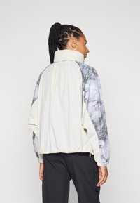Lightweight jacket with a white body and marble-patterned gray sleeves. Features an elastic waistband and cuffs, with a high collar.