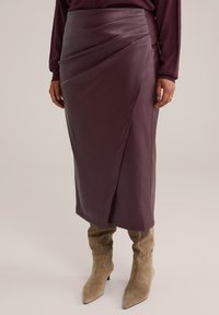 Bordeauxfarbenes Leder-Midirock mit Drapierung, ausgestattet mit einer eleganten, glatten Textur und einem hohen Taillen-Design. Kombiniert mit beigen High-Heels-Stiefeln.
