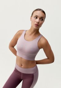 Sportovní podprsenka a legíny v jemné levandulové barvě s decentními tyrkysovými akcenty. Hladký, atletický materiál, přiléhavý střih, vysoký pas na legínách.