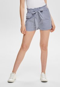 Pruhované šortky v modro-bílé látce, s volánovým pasem a zavazováním, se dvěma předními kapsami. Nosit s bílými teniskami.