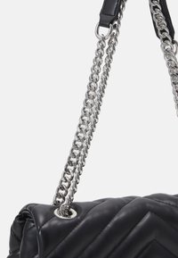 Black leather handbag with a quilted design, featuring silver chain straps and metal hardware. Smooth texture and metal accents are notable.