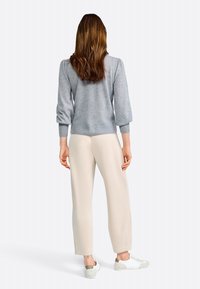 Lichtgrijze pullover met opgeblazen mouwen, geribbelde manchetten en zoom. Gecombineerd met beige op maat gemaakte broeken en witte sneakers met grijze accenten.