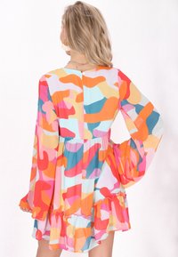 O rochie colorată, transparentă, cu mâneci evazate și tiv cu volane, având un model abstract în nuanțe de roz, portocalie, albastru și crem.