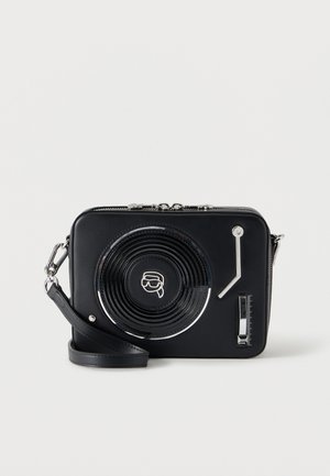 Čierna obdĺžniková crossbody taška navrhnutá ako vinylový prehrávač s ramenom a posuvníkom hlasitosti na prednej strane.