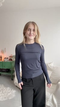 Hosszú ujjú, puha anyagból készült sötétkék felső, testhezálló fazonnal és visszafogott textúrával, párosítva magasan hordott fekete nadrággal.