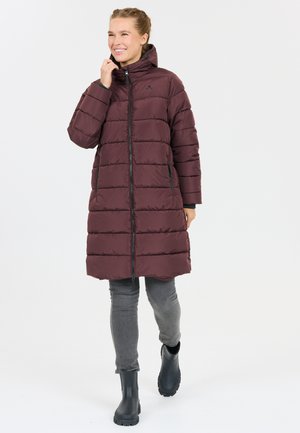 Burgundy pufferjacka med hög krage, dragkedja fram och sidofickor, kombinerad med grå byxor och svarta vattentäta stövlar. Slät textur.