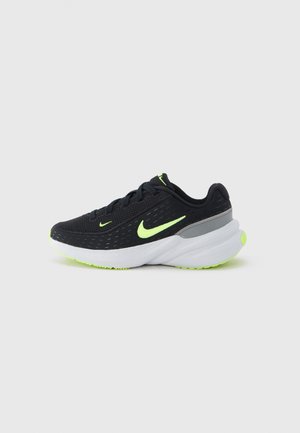 Black Nike running shoe with neon yellow swoosh logos, white cushioned sole, and gray heel detail placed on a plain white background.