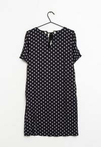 Czarna sukienka z krótkim rękawem w biały trójkątny wzór, z dekoltem w kształcie V z tyłu, wiązanym zapięciem oraz bocznymi rozcięciami dla ułatwienia ruchu.
